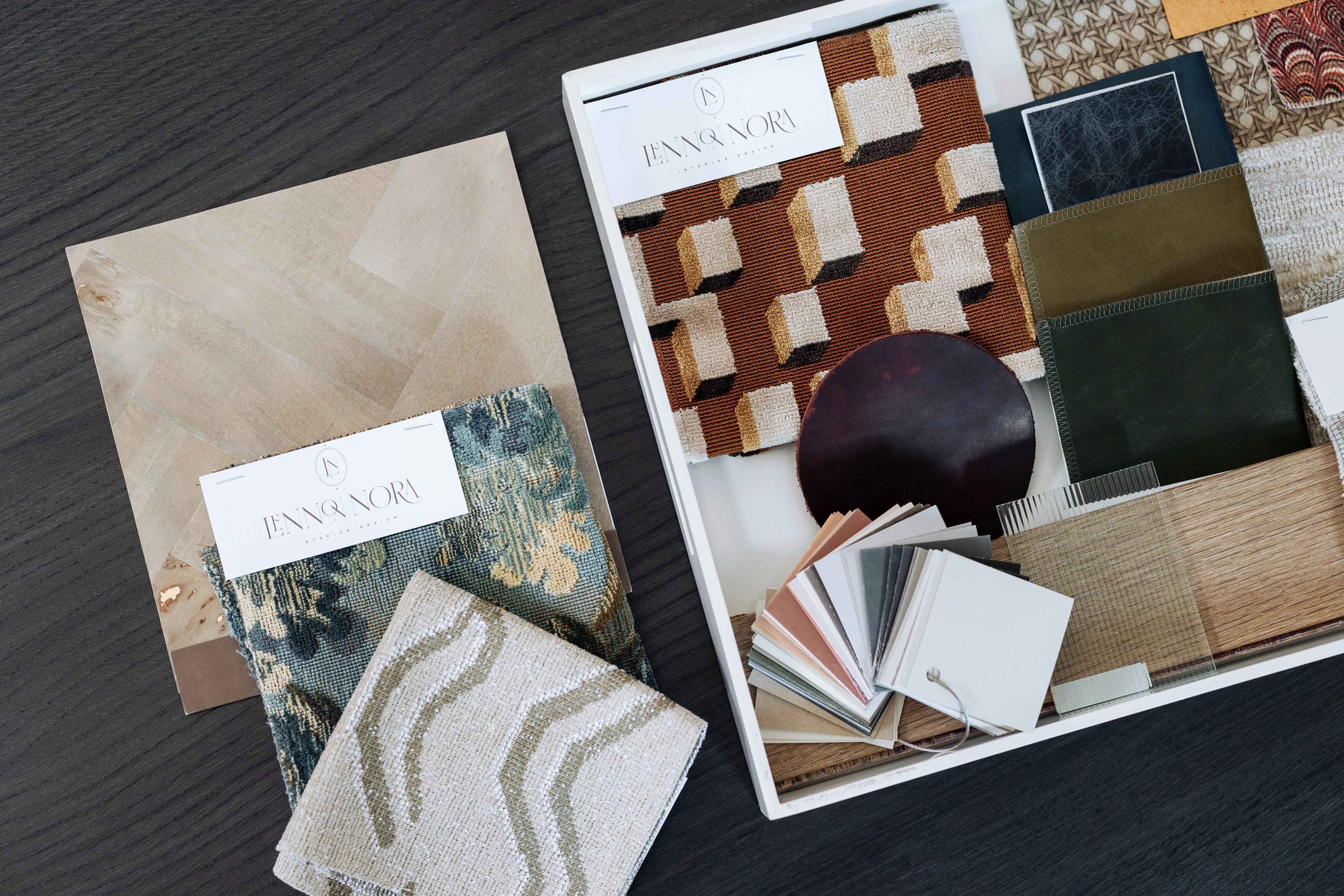 Hands selecting fabric and leather samples against inspiration board