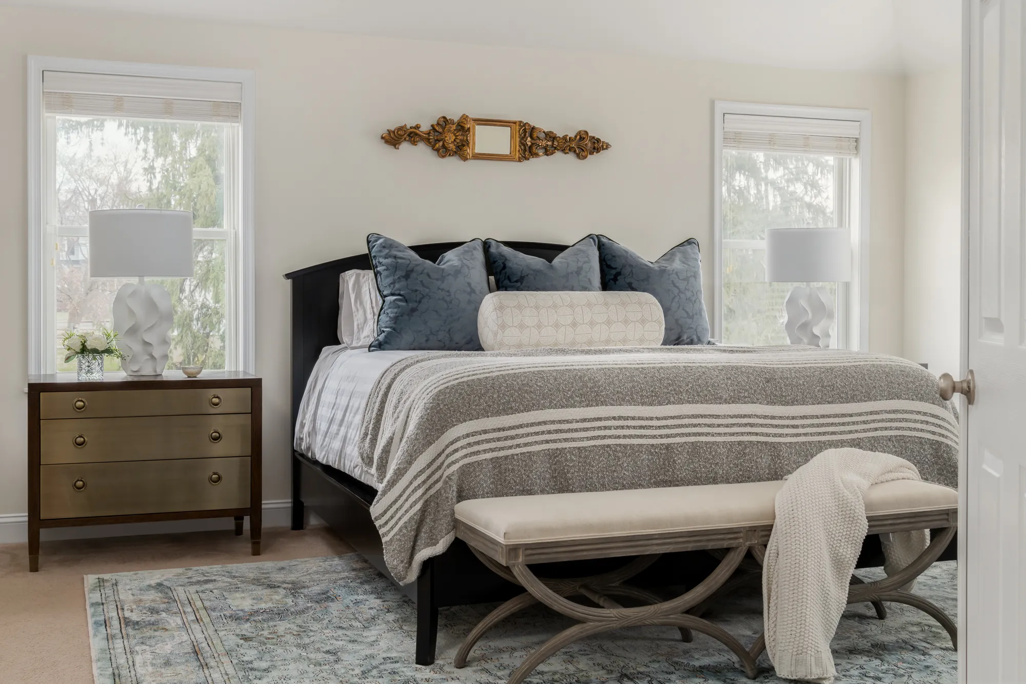 Primary bedroom with iron bed frame and layered neutral bedding