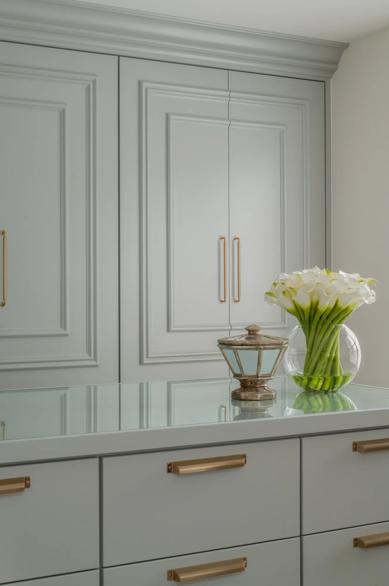 Closet cabinetry detail with calla lilies and brass pulls