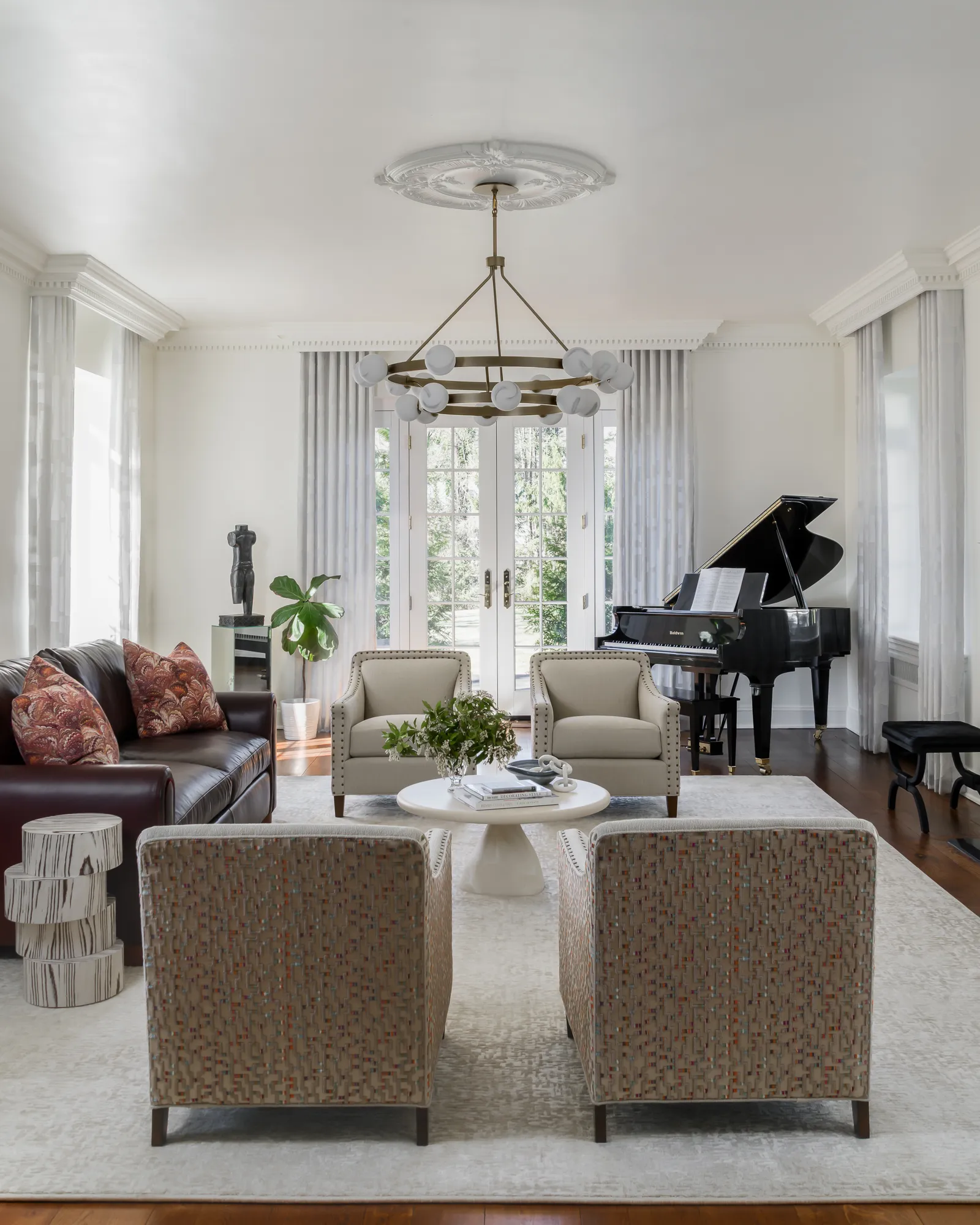 Formal living room with grand piano, brass globe chandelier, and French doors to the garden