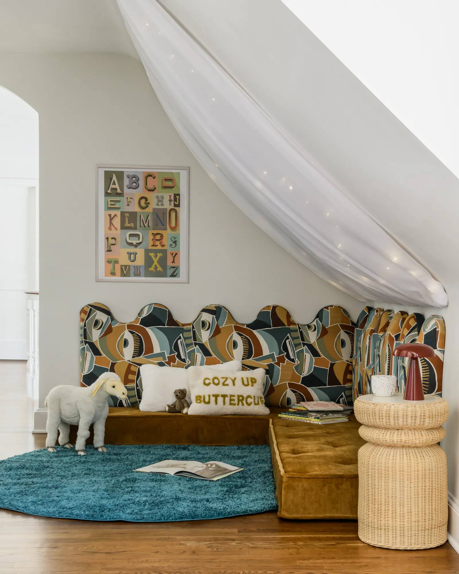 Whimsical under-stair reading nook with patterned headboard, canopy, and alphabet art