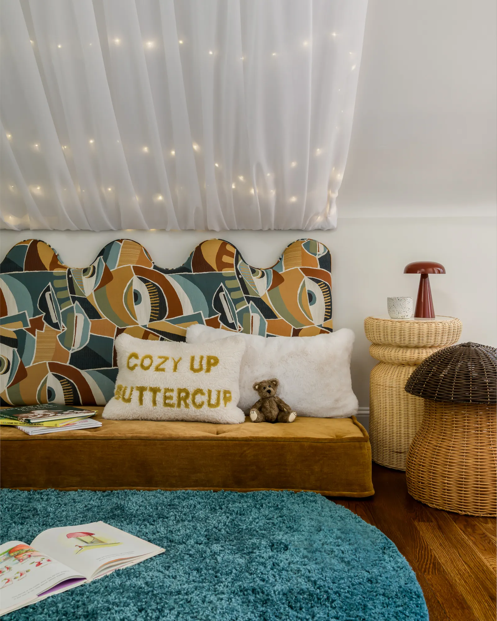 Reading nook side view with sheer canopy, wicker table, and teal rug