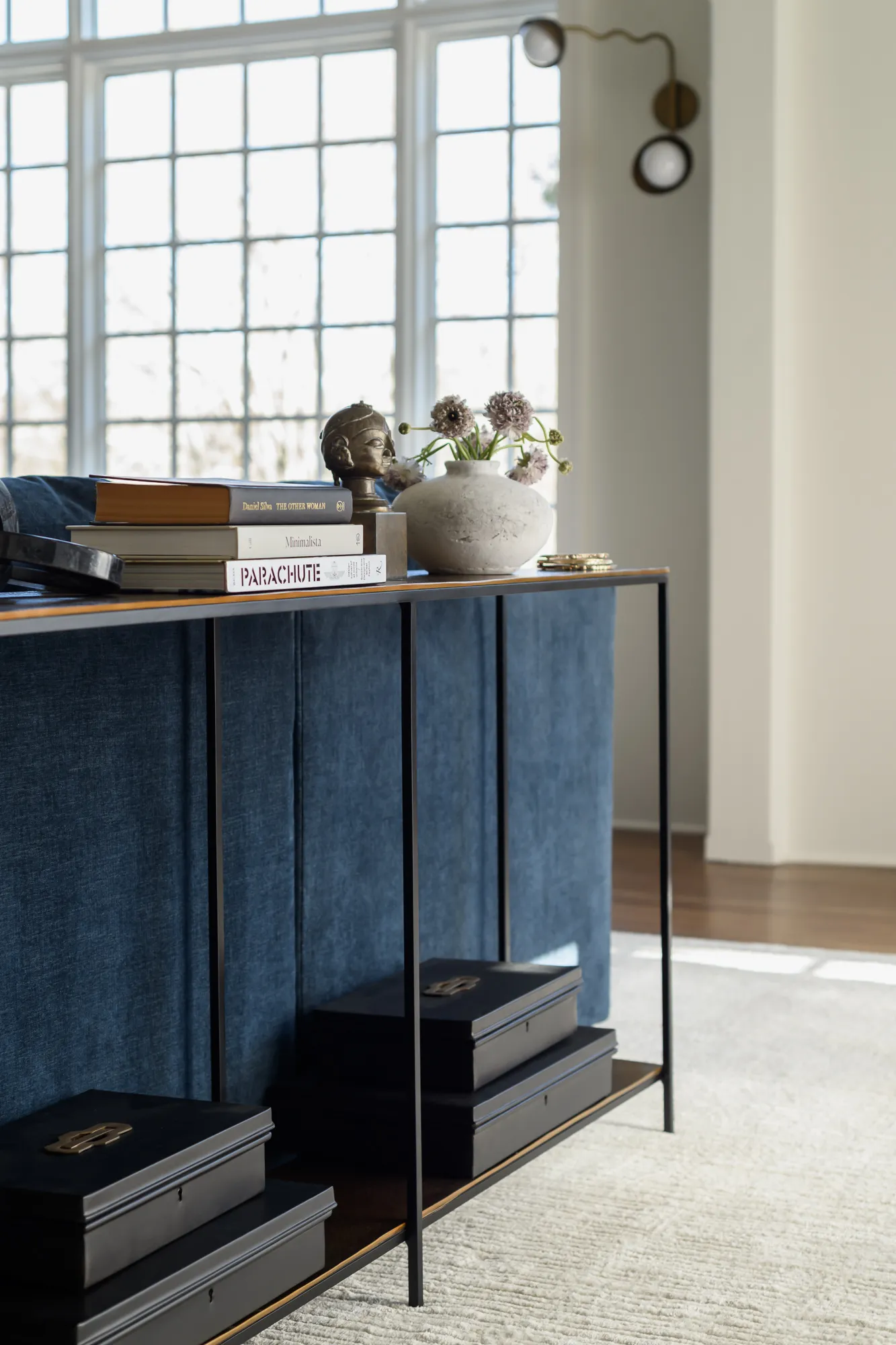 Console table with stacked books, bronze bust, and stone vase