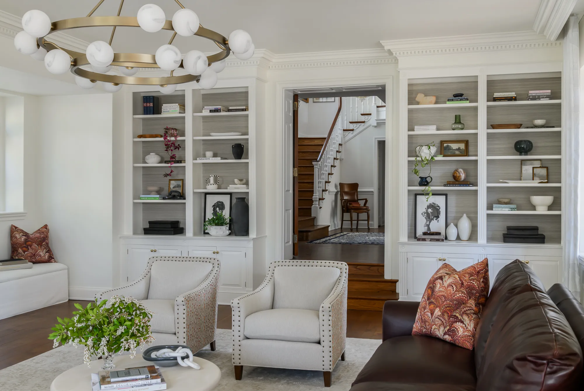 Built-in bookcases with grasscloth backing framing the entry to the foyer