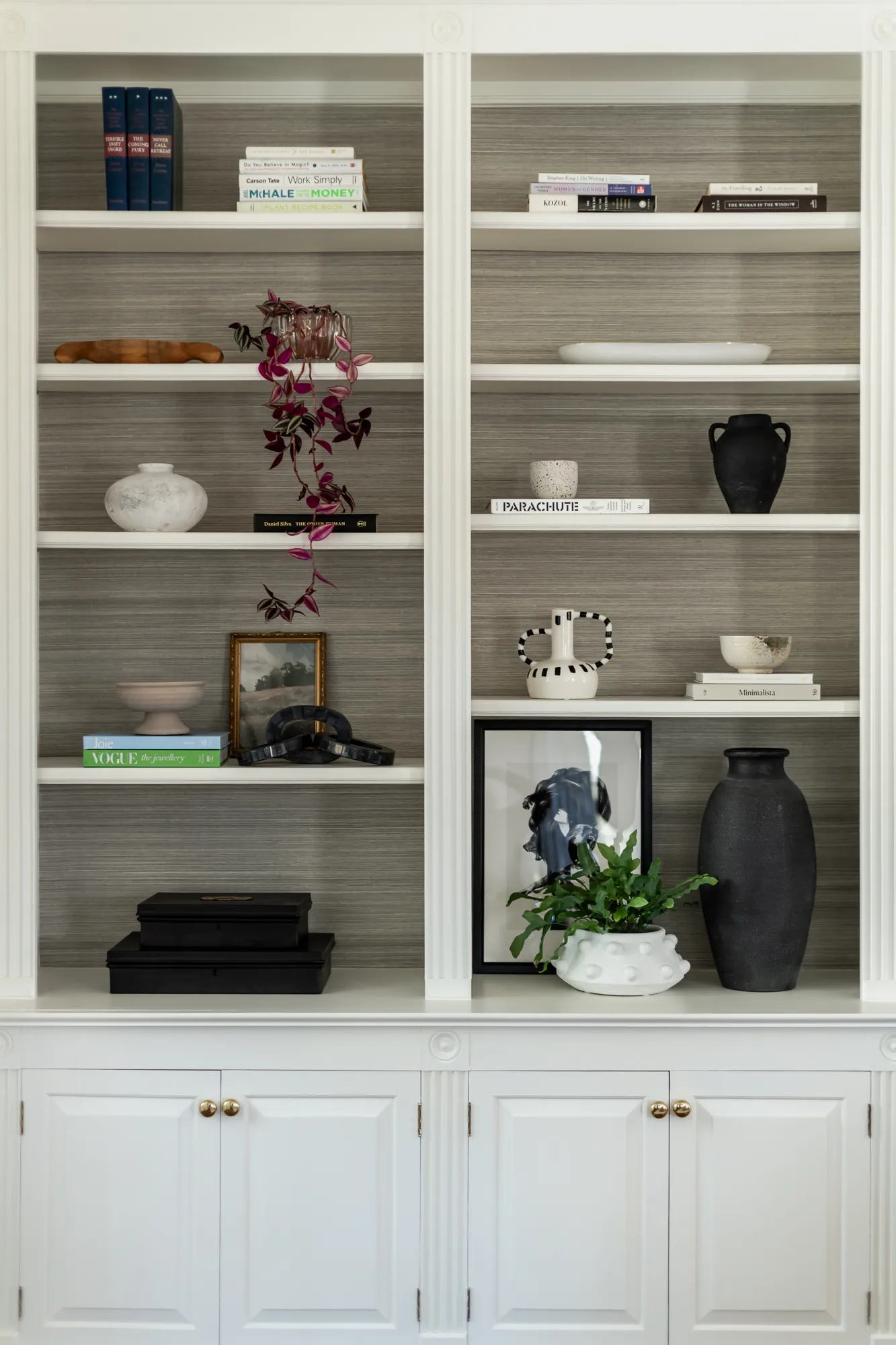 Bookshelf styling with collected ceramics, art prints, and trailing plants