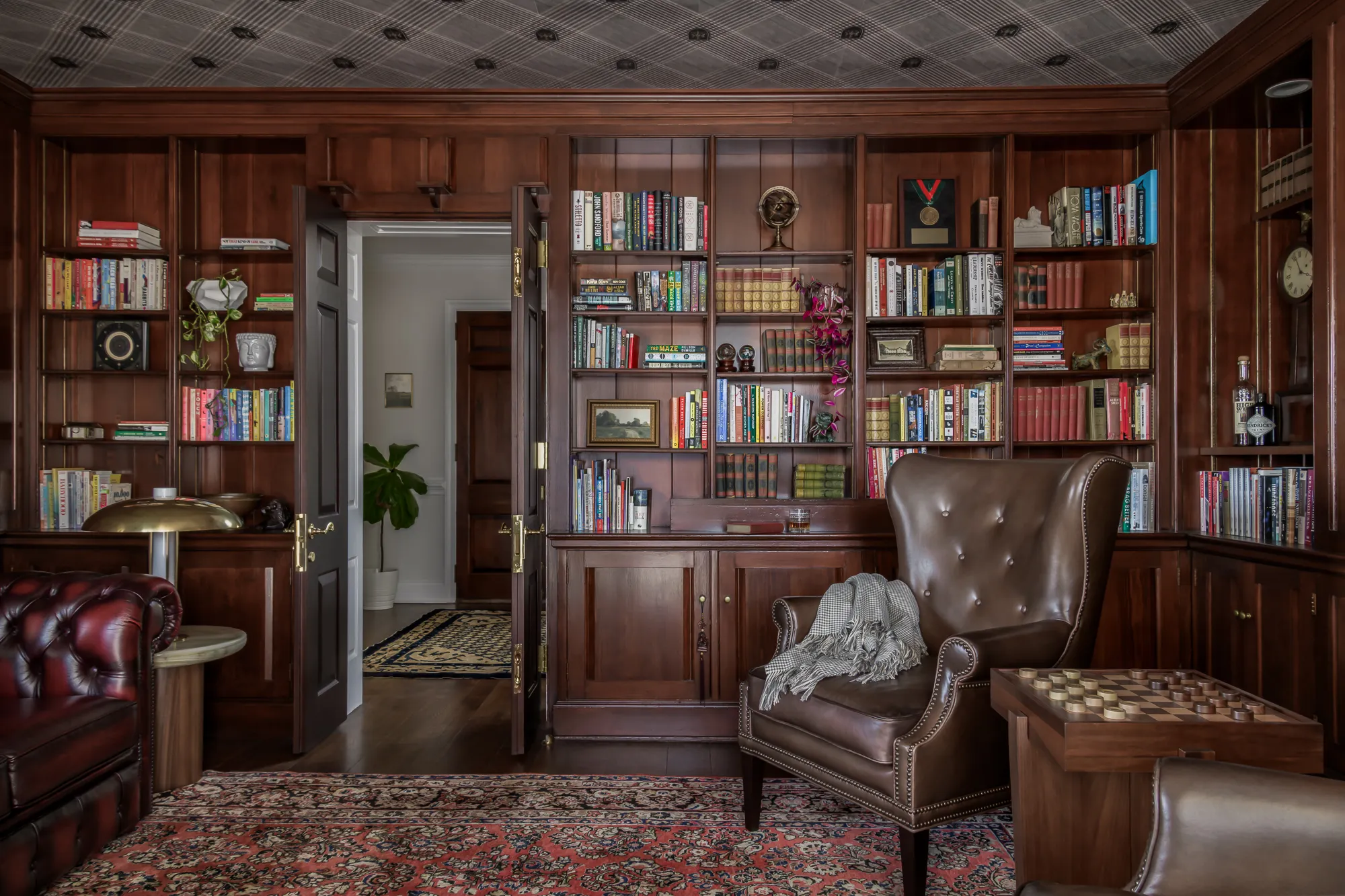 Mahogany-paneled library with floor-to-ceiling bookshelves and leather Chesterfields