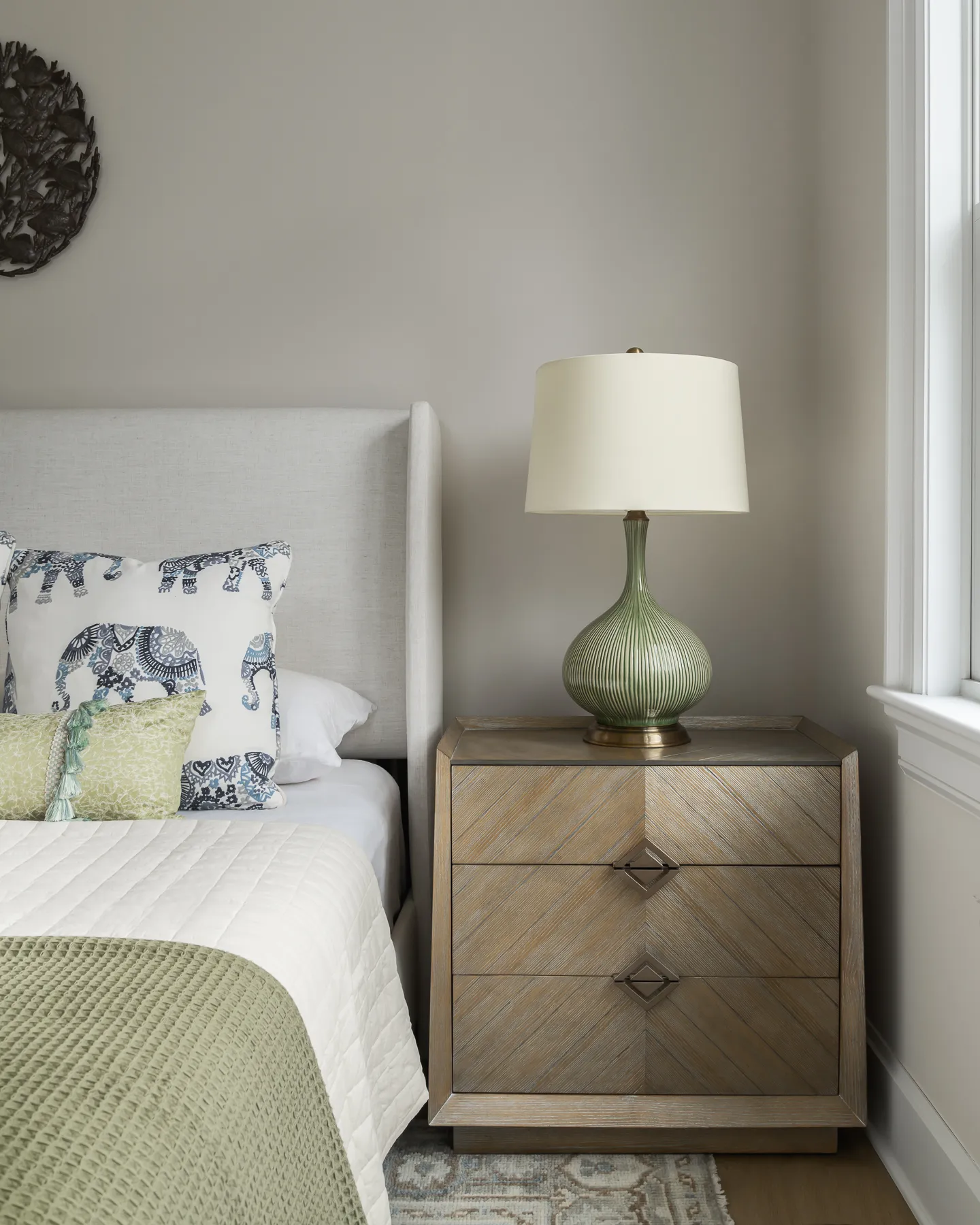 Sage ribbed lamp and elephant-print pillow on chevron-front nightstand