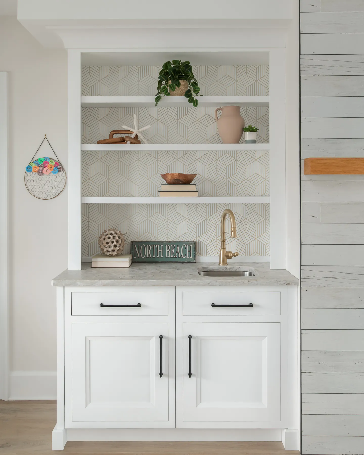 Built-in wet bar with geometric tile backsplash, marble counter, and brass faucet