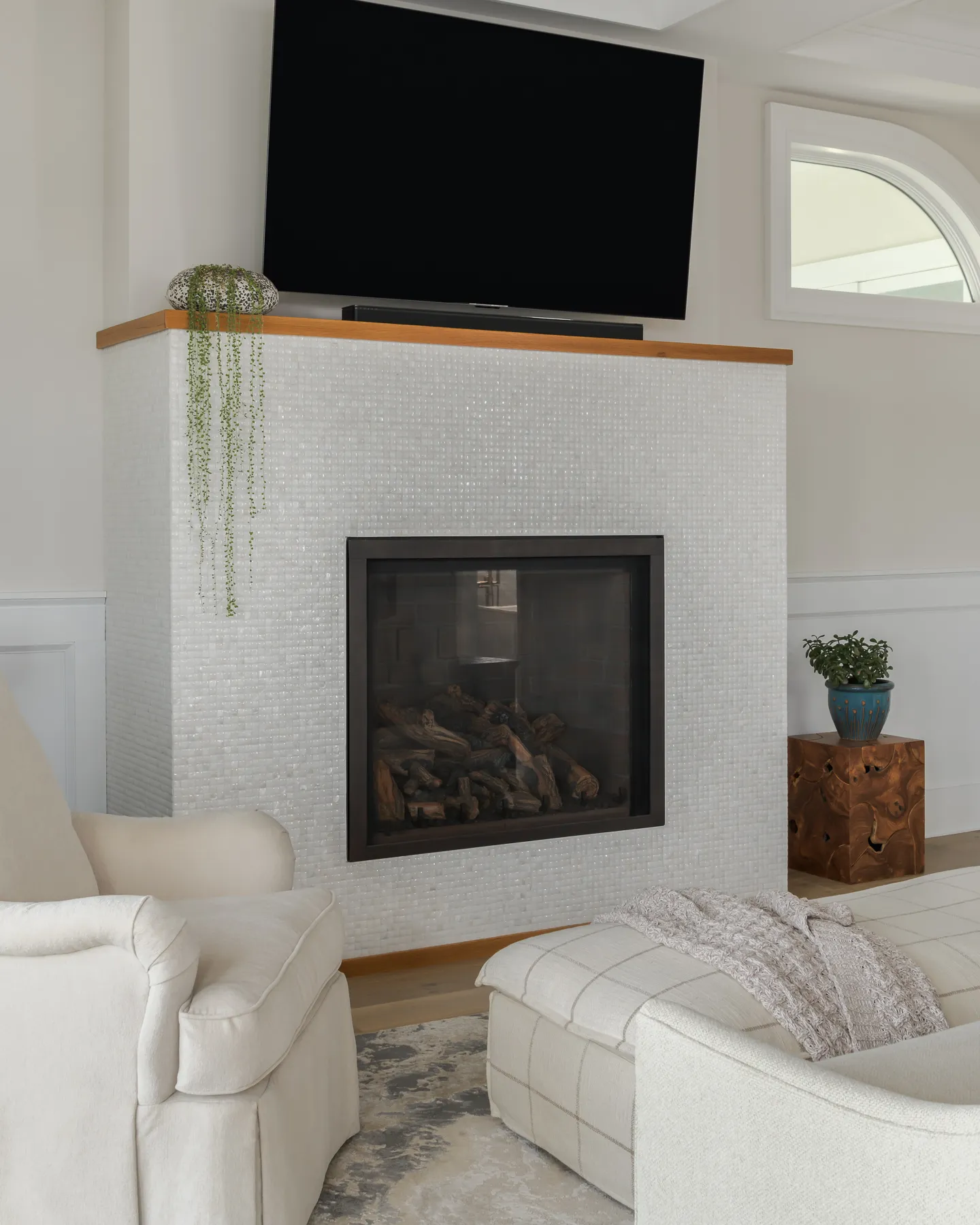 Mother-of-pearl mosaic fireplace with natural oak mantel and trailing succulent