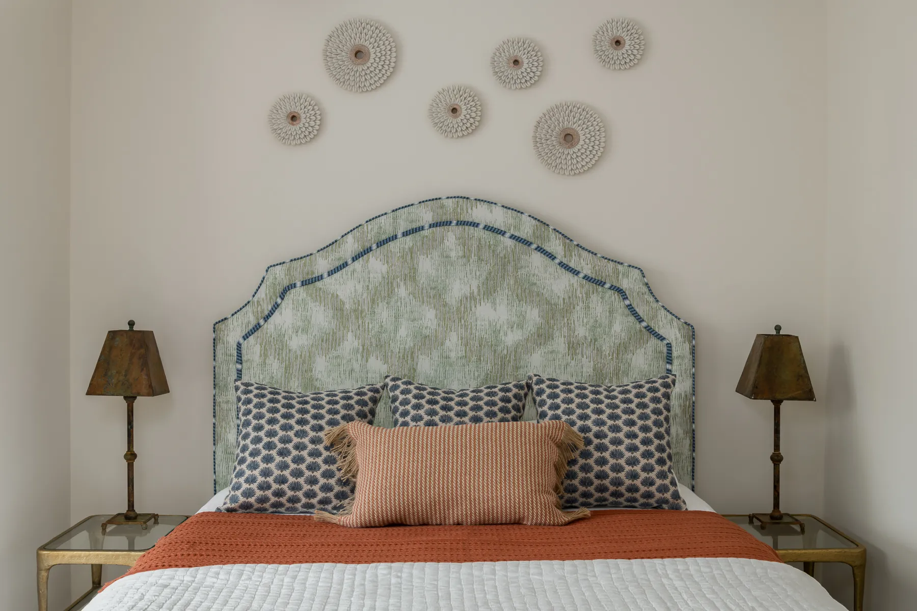 Arched headboard in sea-green ikat with sea urchin wall medallions and terracotta bolster