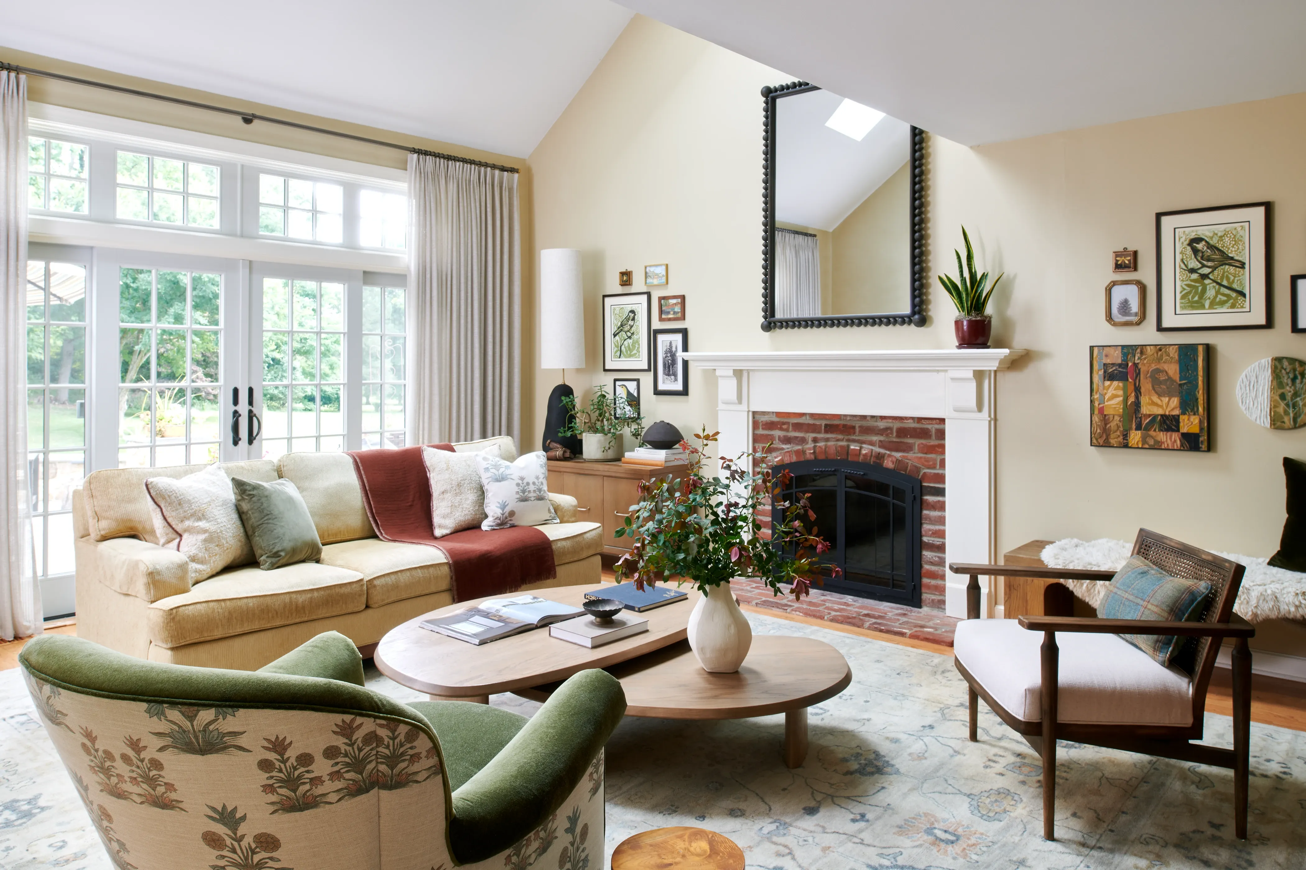 Vaulted family room with brick fireplace, nature gallery wall, and botanical area rug