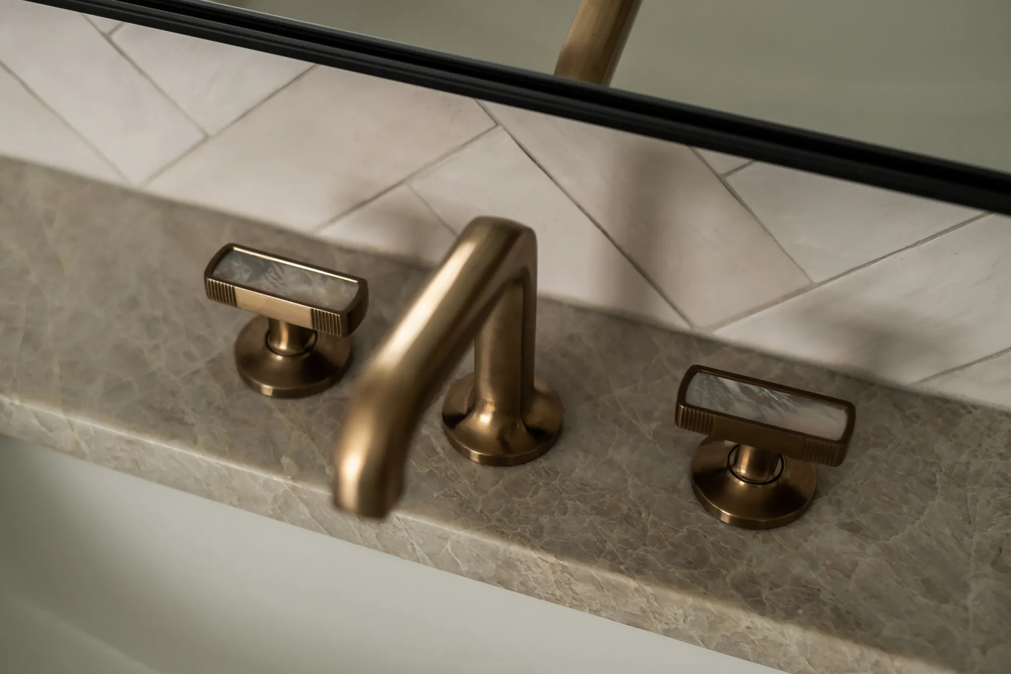 Brass faucet with mother-of-pearl handles on marble counter